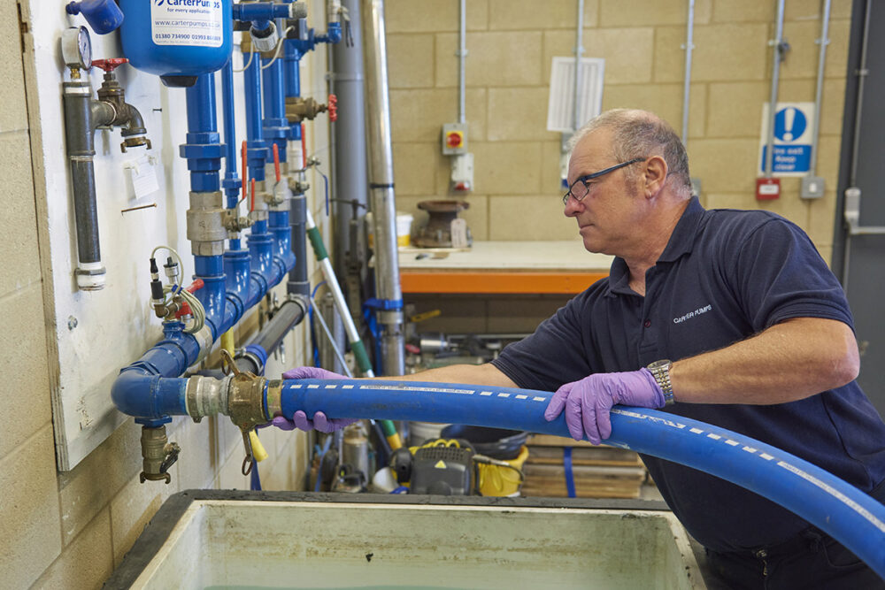 Engineer testing water pressure using blue hose