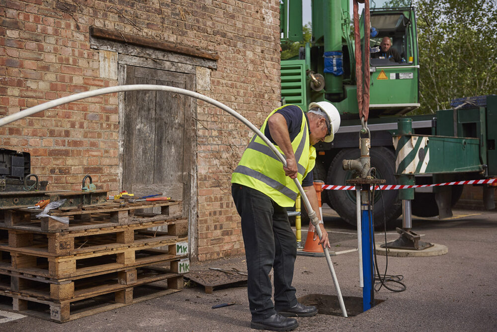 Engineer inserting hose into borehole